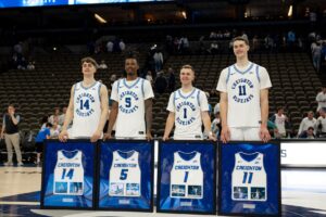 Creighton's four graduating seniors, Sami Osmani, Jamiya Neal, Steven Ashworth and Ryan Kalkbrenner stand together during the Senior Day celebration with framed jerseys standing up in front of them.