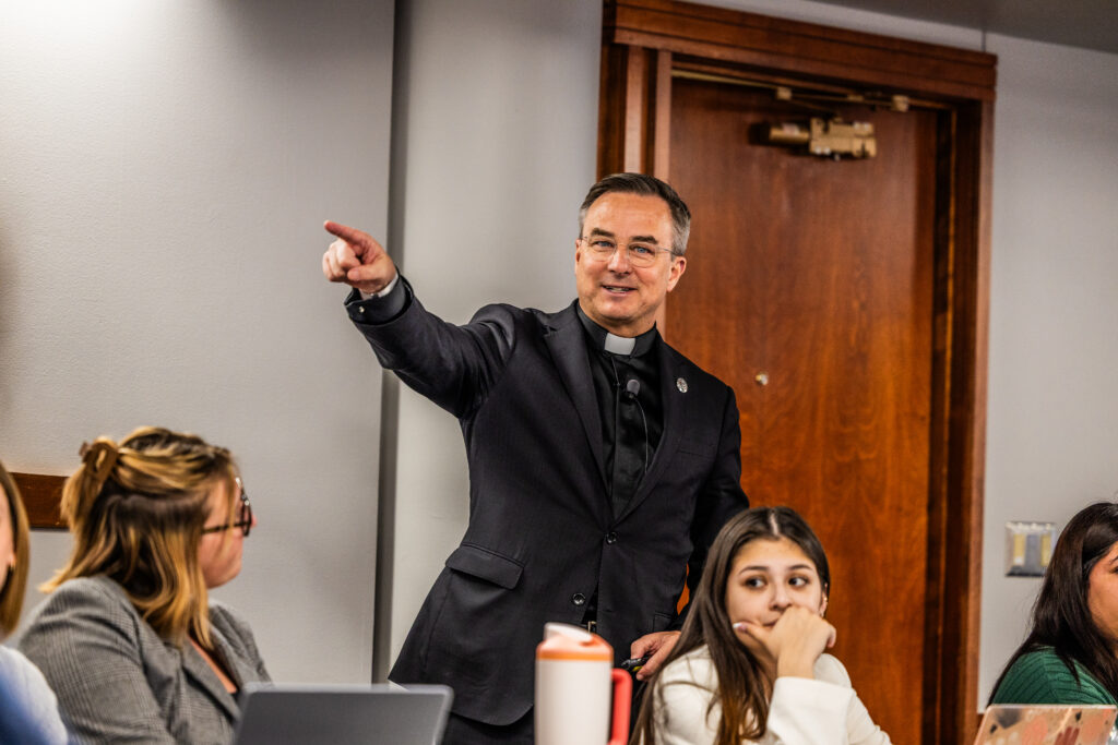A man, the Rev. Hendrickson, points while speaking to students.