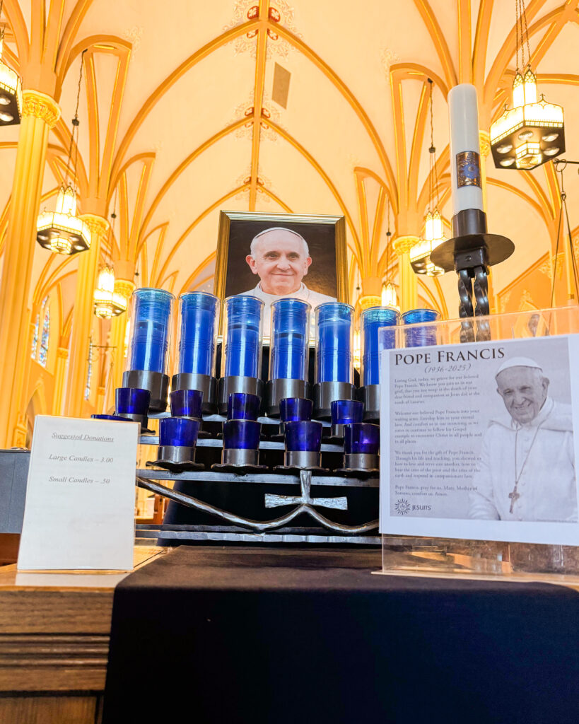 A table in St. John's Church has candles, a photo of Pope Francis and a framed prayer
