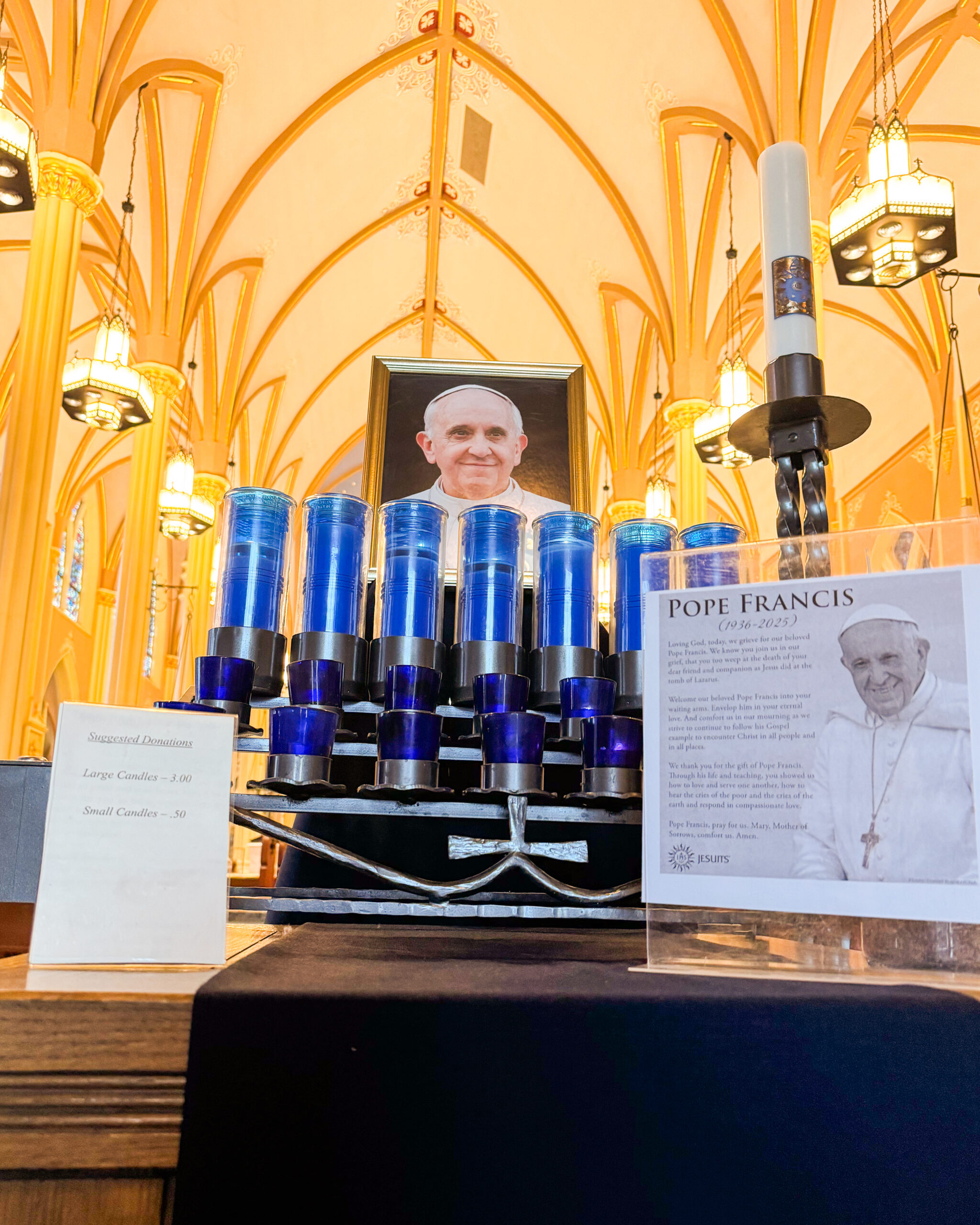A table in St. John's Church has candles, a photo of Pope Francis and a framed prayer