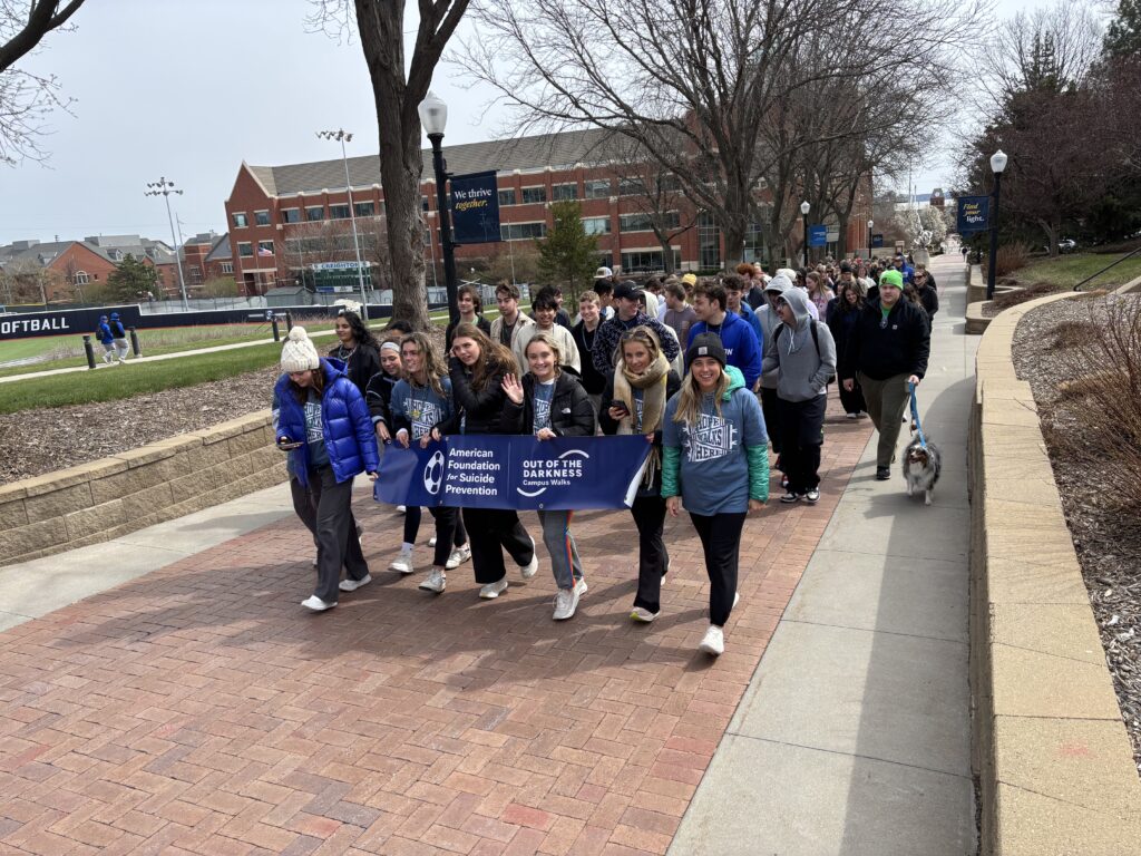 A group marches while carrying a banner for the American Foundation for Suicide Prevention